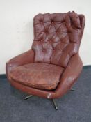 A mid 20th century buttoned leather upholstered armchair on swivel base