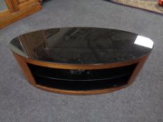 An oval glass top television stand in a walnut finish