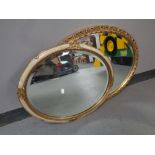 A gilt framed oval bevelled mirror together with a further cream and gilt framed bevelled mirror