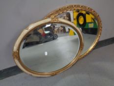 A gilt framed oval bevelled mirror together with a further cream and gilt framed bevelled mirror