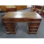 A mahogany twin pedestal writing desk fitted nine drawers with green tooled leather inset panel