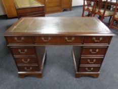 A mahogany twin pedestal writing desk fitted nine drawers with green tooled leather inset panel