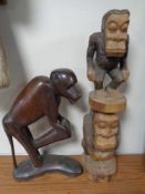 A 20th century African carved hardwood statue of a monkey, together with another similar,