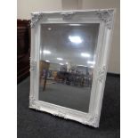 An ornate white painted bevelled overmantel mirror