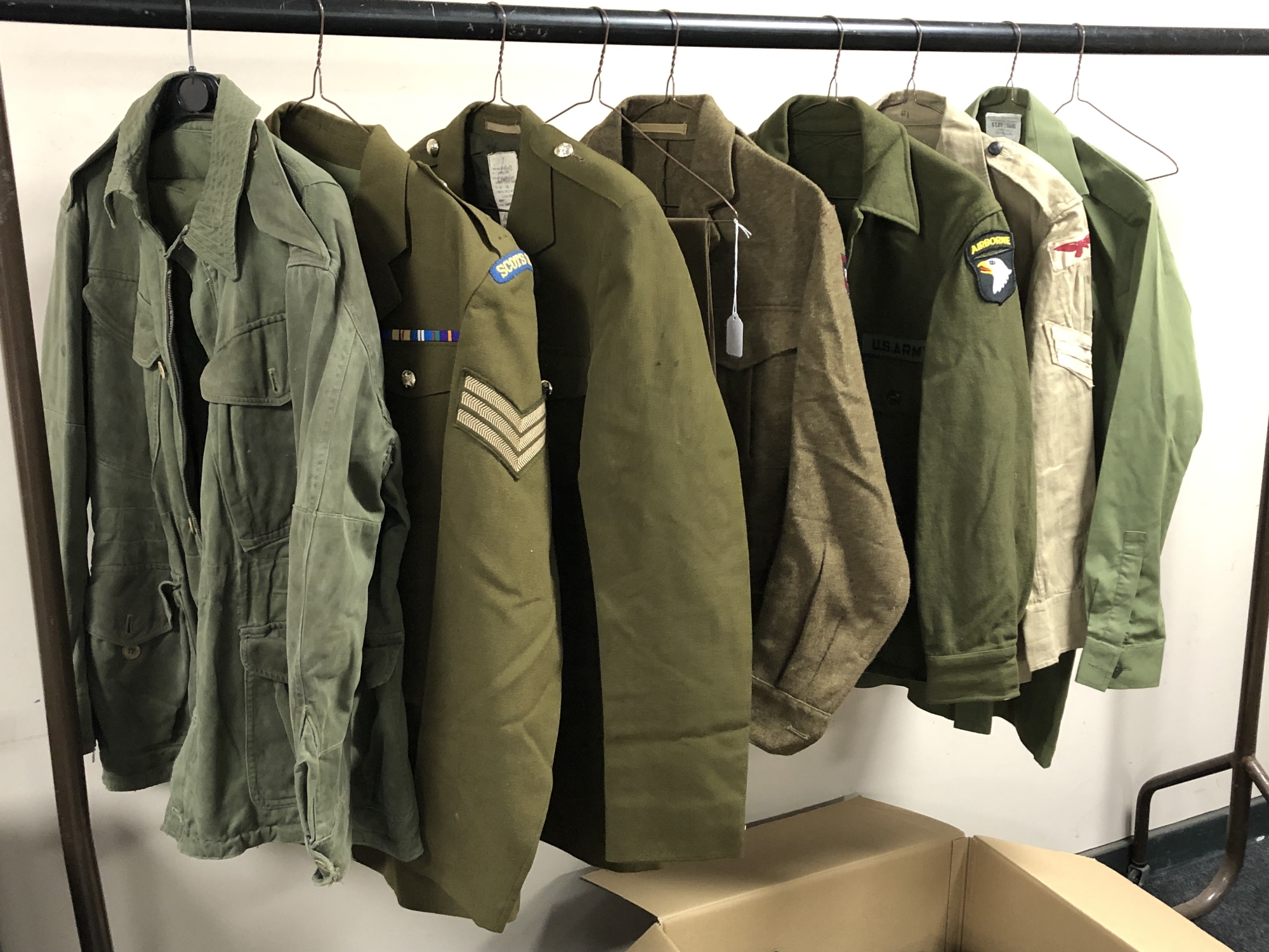 A rail of Second World War and later military uniforms comprising combat smock,