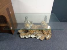 A glass topped coffee table on a figural tiger with cub base