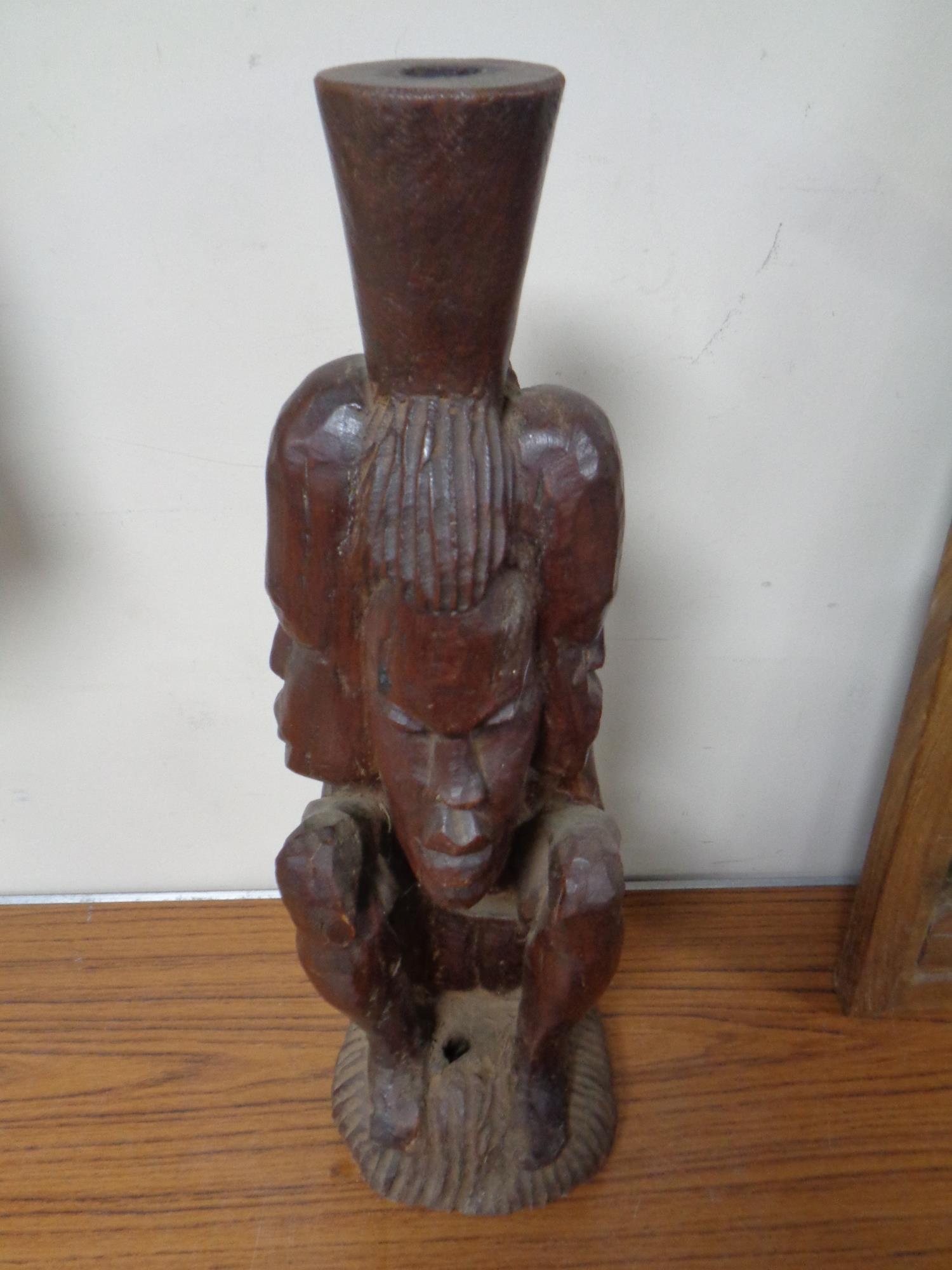 A 20th century African carved hardwood statue of a seated figure with four heads,