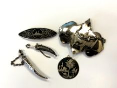 Two Arabic silver brooches in the form of Jambiya knives, together with a silver niello belt buckle,