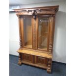 A late 19th century carved oak double door bookcase fitted with cupboards below decorated with