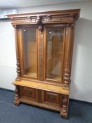 A late 19th century carved oak double door bookcase fitted with cupboards below decorated with