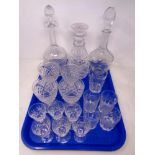 A tray of three cut glass decanters with stoppers, set of four wine glasses,