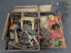 A box and a wooden tray containing vintage Hornby tin plate railway track, buildings, accessories,