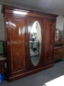 A late Victorian inlaid mahogany triple door wardrobe with mirrored central panel