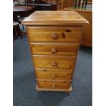 A narrow pine five drawer chest