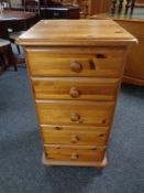 A narrow pine five drawer chest