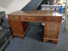 A mahogany twin pedestal writing desk fitted with nine drawers and tooled brown leather insert