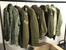 A rail of Second World War and later military uniforms comprising combat smock,