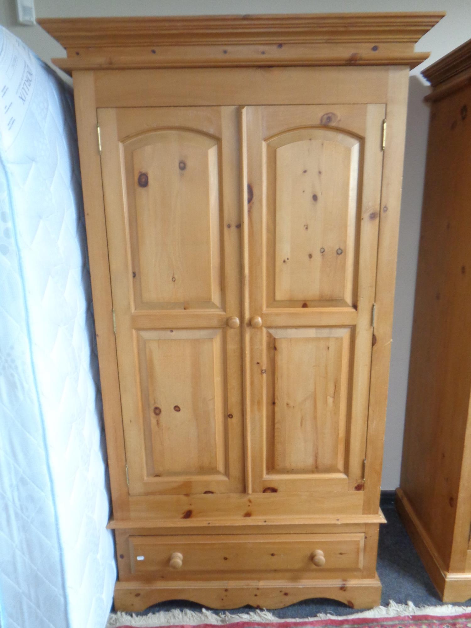 A contemporary pine double door wardrobe fitted with drawer beneath