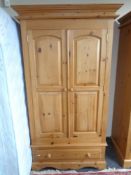 A contemporary pine double door wardrobe fitted with drawer beneath