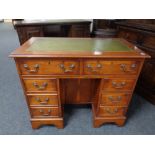 A yew wood kneehole writing desk fitted with eight drawers with green tooled leather panel