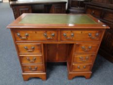 A yew wood kneehole writing desk fitted with eight drawers with green tooled leather panel