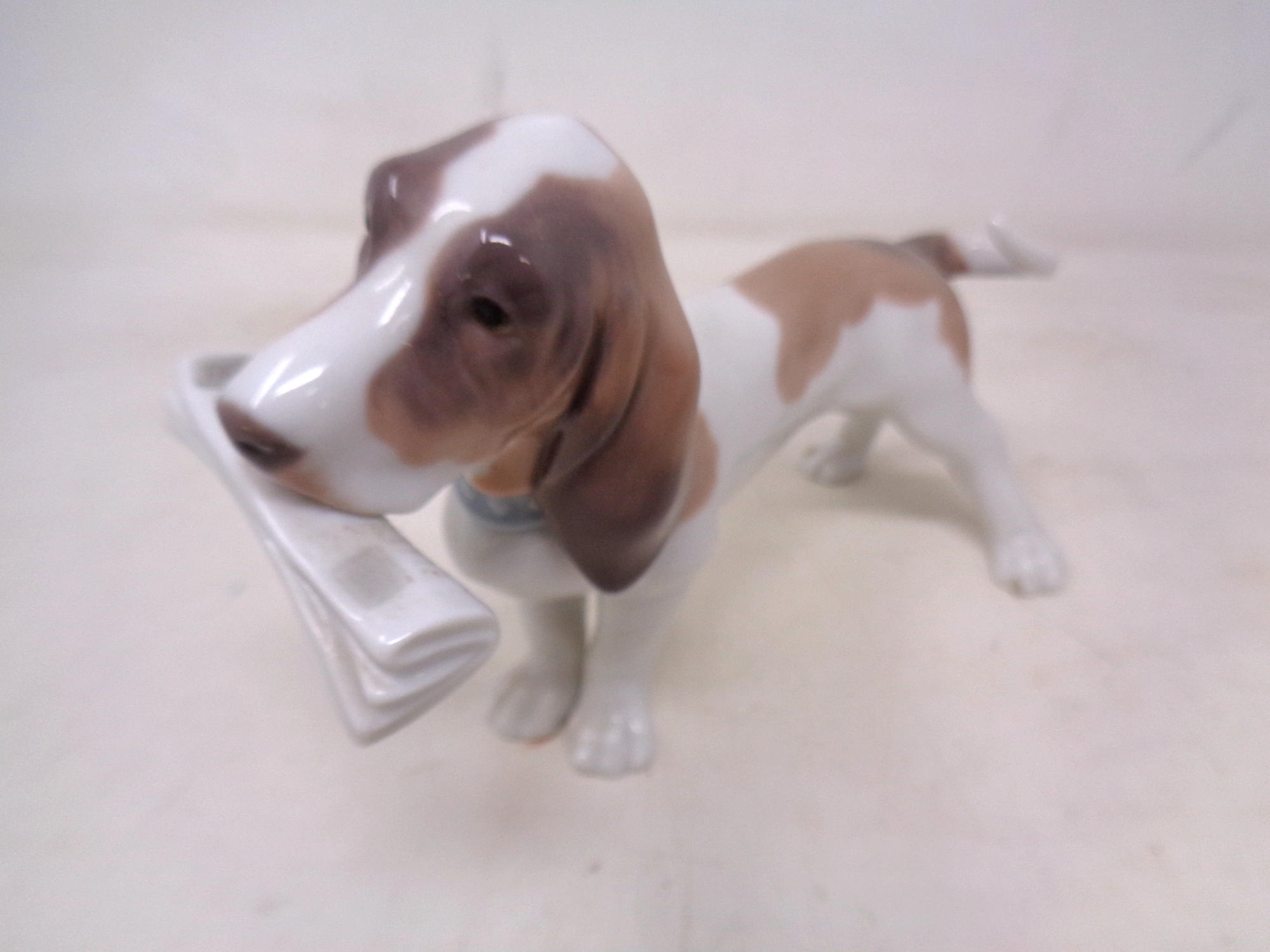 A Lladro figure of a beagle holding a newspaper