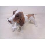 A Lladro figure of a beagle holding a newspaper