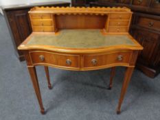 A lady's Sheraton style serpentine fronted yew wood writing desk with green leather panel