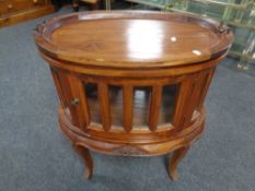 An Indonesian hardwood oval drinks cabinet on raised legs with lift off tray.