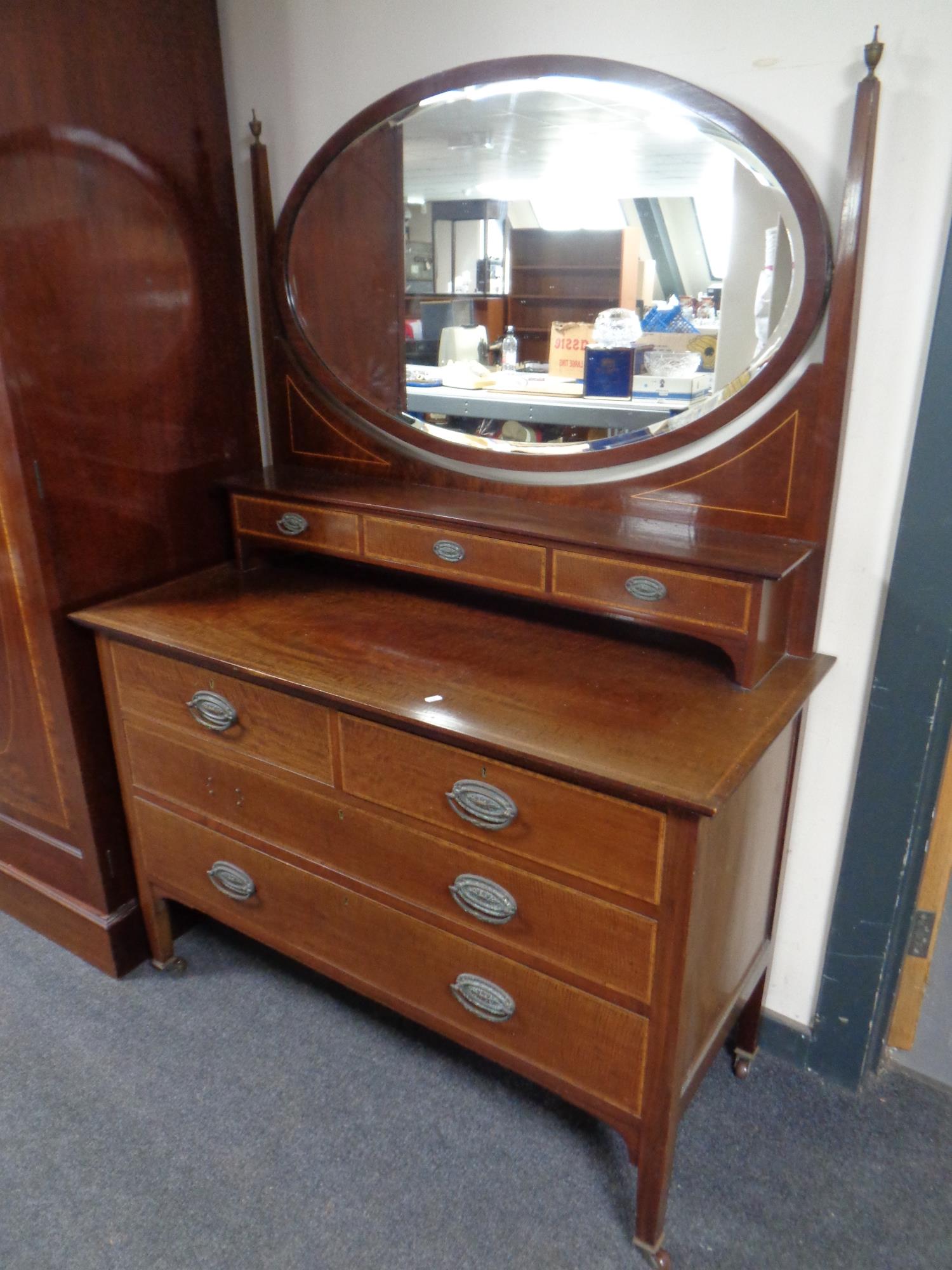 A late Victorian inlaid mahogany four drawer dressing chest with mirror on raised legs