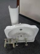 A ceramic sink on pedestal together with pair of brass taps and a bath brass mixer tap.