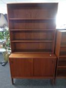 A mid 20th century teak open bookshelf fitted with cupboard beneath