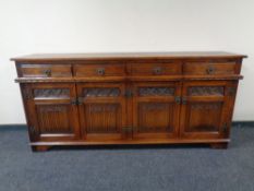 An Old Charm carved oak four drawer four door sideboard.