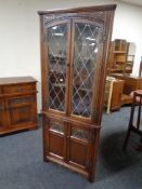 A carved oak Old Charm double door leaded glass display cabinet fitted cupboards beneath.