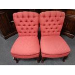 A pair of contemporary buttoned bedroom chairs in red fabric