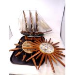 A tray of two teak sunburst wall clocks together with a model of a galleon