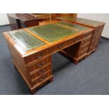 A yew wood nine drawer twin pedestal desk with three tooled leather panels