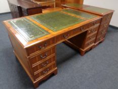 A yew wood nine drawer twin pedestal desk with three tooled leather panels
