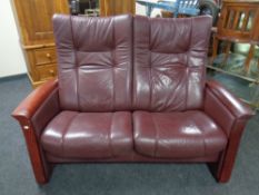 A Himolla manual reclining two-seater settee upholstered in a Burgundy leather.