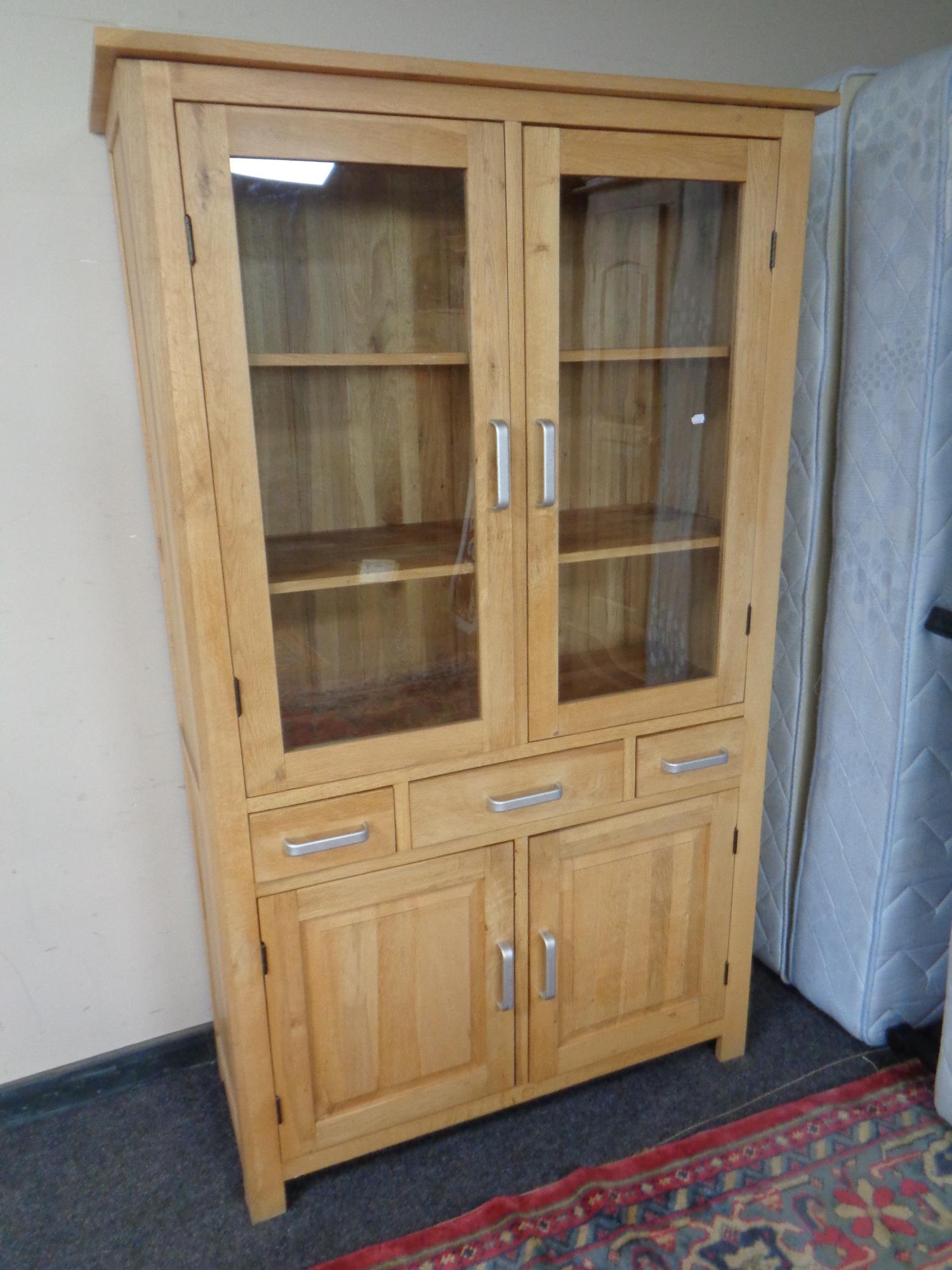 A contemporary oak double door display cabinet fitted with double door cupboard and three drawers