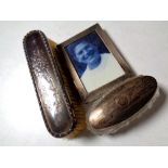 A silver photo frame, silver-backed brush, silver-topped cut glass dressing table jar.