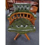 A yew wood captain's desk chair in green buttoned leather