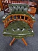 A yew wood captain's desk chair in green buttoned leather