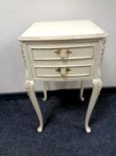 A cream and gilt two drawer bedside stand