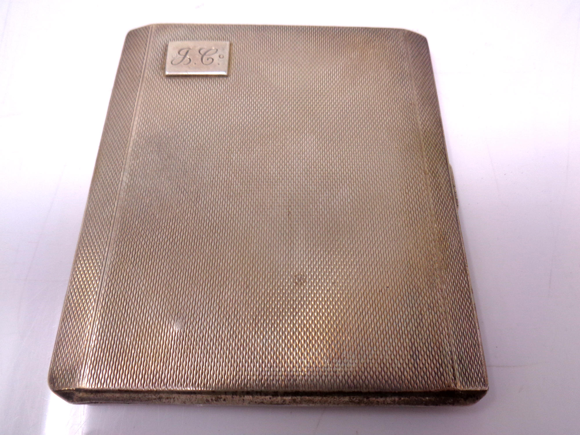 A silver cigarette case with engine turned decoration together with a silver heart shaped bookmark