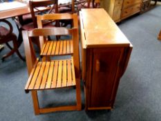 A drop leaf storage kitchen table together with four folding chairs in an oak finish