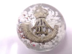 A glass paperweight with inset Durham Light Infantry cap badge