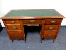 An Edwardian mahogany twin pedestal knee hole desk fitted with seven drawers and green leather