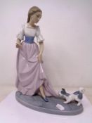 A Nao figure of a girl with puppy tugging dress