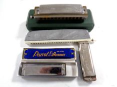A group of five harmonicas including Hohner, Tower,
